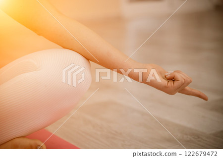 Girl does yoga. Young woman practices asanas on a beige one-ton background. 122679472