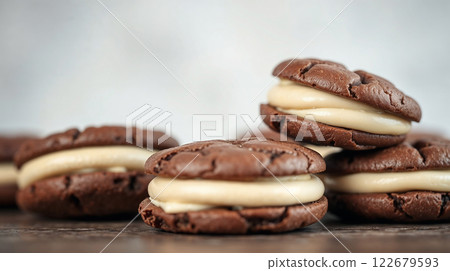 Delicious chocolate cookies filled with sweet cream resting on wooden table 122679593