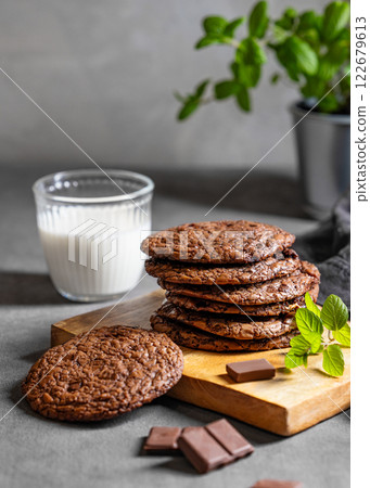 Stack of chocolate cookies on a wooden board on a dark background with a glass of milk Stack of chocolate cookies on a wooden board on a dark background with a glass of milk 122679613