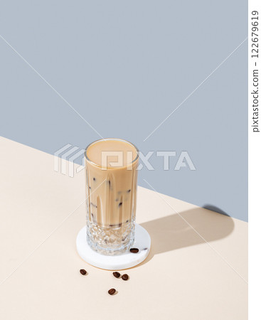 Cold latte coffee in a tall glass with alternative milk on a marble stand on yellow blue background 122679619