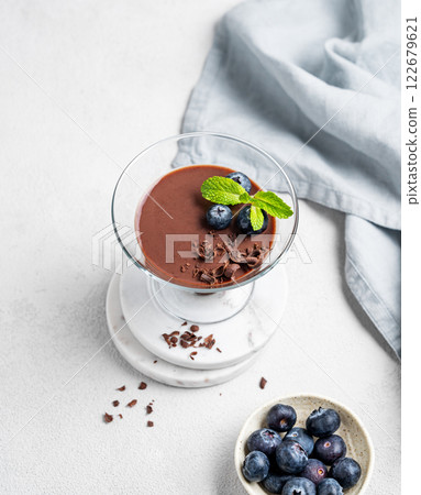 Chocolate pudding in a glass with fresh blueberries and mint on a light background 122679621