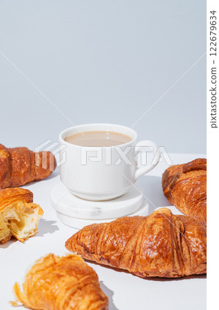 Fresh croissants on a light background with freshly brewed coffee with milk. Fresh croissants on a light background with freshly brewed coffee with milk. 122679634