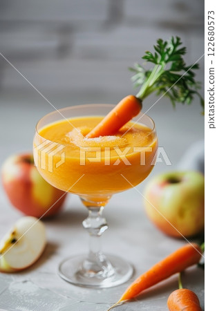 This creative smoothie combines the flavors of carrot and apple, presented in an appealing glass shaped like an apple. The vibrant orange color is enhanced by a fresh carrot garnish 122680573