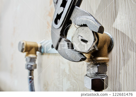 Tightening pipe plugs with an adjustable pliers wrench ensures secure seal on plumbing system bracket. 122681476