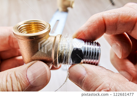 Applying plumbing flax ensures leak proof connection while installing male threaded reducer into brass plumbing fitting. 122681477