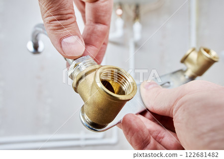 Hands assembling water pipe with metal bracket and connector. 122681482
