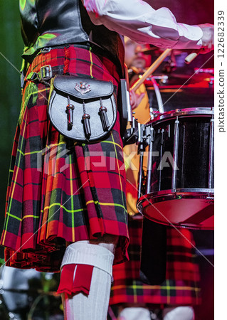 Colorful kilt and drum showcased during lively performance at traditional music festival, musician wearing a bright kilt, playing drum, festive mood 122682339