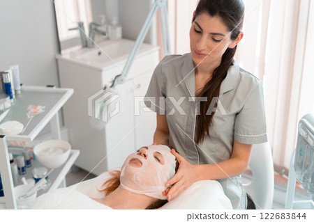 Massage therapist applying hydrating face mask to Massage therapist applying hydrating face mask to 122683844