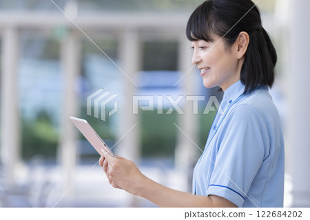 Facility staff image: Profile of a middle-aged woman holding a tablet Facility staff image: Profile of a middle-aged woman holding a tablet 122684202