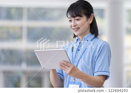 Image of a middle-aged female facility staff member holding a tablet Image of a middle-aged female facility staff member holding a tablet 122684203