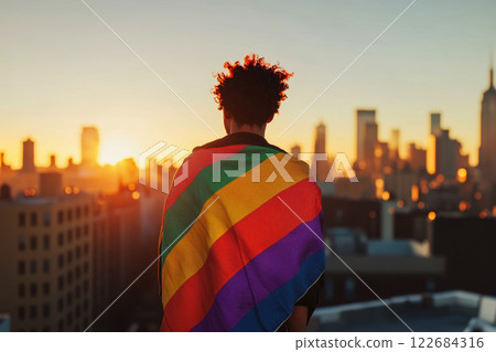 a young man wrapped in a rainbow flag standing on rooftop background. Concept of The LGBT community. 122684316
