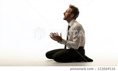 a distressed business man kneeling on isolated white background. 122684510