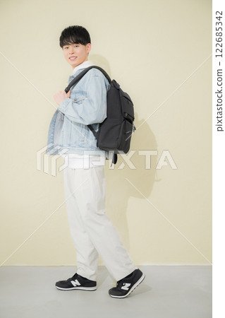 圖片為一名大學生或 20 多歲的年輕男子背著背包,黃色背景,右側有影印空間 圖片為一名大學生或 20 多歲的年輕男子背著背包,黃色背景,右側有影印空間 122685342