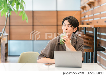 一名男子在電腦前工作時透過喝綠色冰沙、綠色果汁和蔬菜汁來禁食和節食 122686090