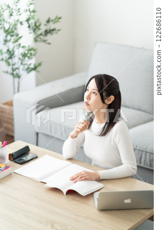 一名 30 多歲的女性正在查閱參考書，以進行再培訓 122686110