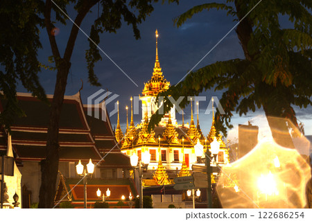 Sunset time of beautiful lights decorated on trees and Wat Ratchanaddaram Woraviharn Temple. This is a place of respect and tourism for Buddhists around the world Sunset time of beautiful lights decorated on trees and Wat Ratchanaddaram Woraviharn Temple. This is a place of respect and tourism for Buddhists around the world 122686254