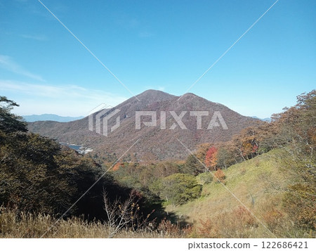 A towering mountain with blue skies and autumn leaves A towering mountain with blue skies and autumn leaves 122686421