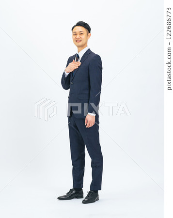 Full-body photo of a middle-aged male business person with his hand on his chest 122686773