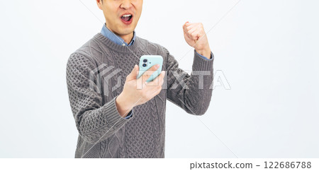 A middle-aged man doing a fist pump while looking at his smartphone 122686788