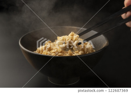 Pick up oatmeal from a bowl with chopsticks 122687369