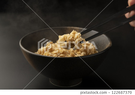 Pick up oatmeal from a bowl with chopsticks 122687370