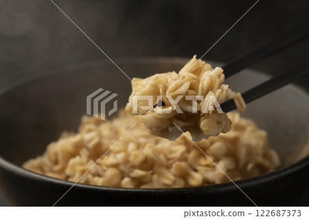 Pick up oatmeal from a bowl with chopsticks 122687373