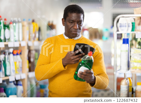 Male shopper checks a QR code on a dishwashing sponge label in supermarket Male shopper checks a QR code on a dishwashing sponge label in supermarket 122687432