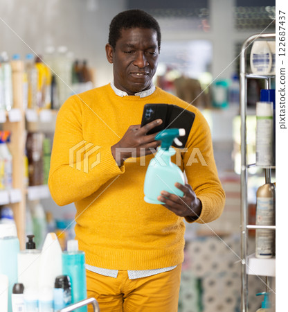 Male shopper checks QR code on spray glass cleaner for windows label in supermarket 122687437