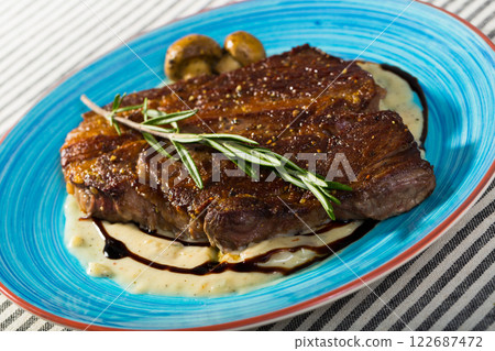 Fried beef steak with mushrooms sauce branch of rosemary at plate 122687472