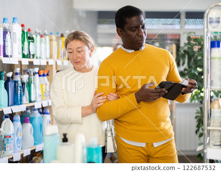Couple woman and man with phone choose household chemicals 122687532