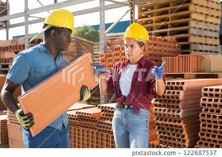Female manager pointing to worker where to carry bricks 122687537