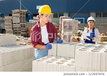 Female builders with hollow concrete blocks in outdoor warehouse Female builders with hollow concrete blocks in outdoor warehouse 122687648
