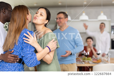 Asian woman kissing female friend arriving for home get-together Asian woman kissing female friend arriving for home get-together 122687664