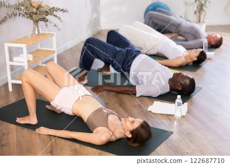 Young woman doing Setu Bandha Sarvangasana in yoga studio 122687710