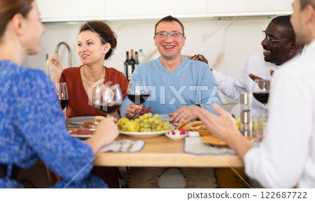 Multiethnic women and men friends chatting and drinking Multiethnic women and men friends chatting and drinking 122687722