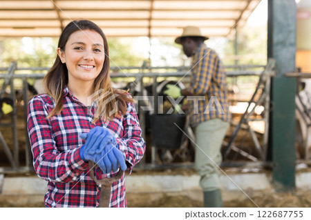 Portrait of a young positive laborer woman standing in the yard of a livestock farm 122687755