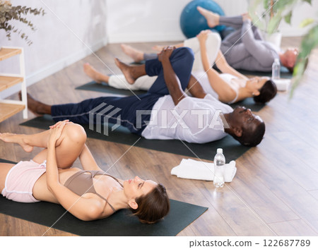 Young woman doing stretching Ardha Pawanmuktasana in yoga studio Young woman doing stretching Ardha Pawanmuktasana in yoga studio 122687789