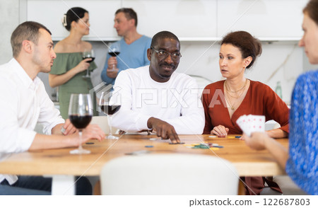 African American man playing poker with friends at kitchen table 122687803