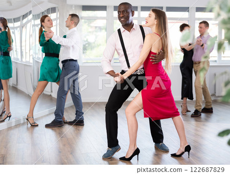 Woman with African man dancing waltz in couple during lesson at studio 122687829