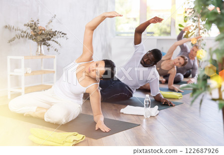 Women and men practicing yoga lesson at sport club Women and men practicing yoga lesson at sport club 122687926