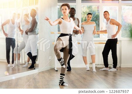 Female ballet instructor demonstrating movements to group of dancers 122687937