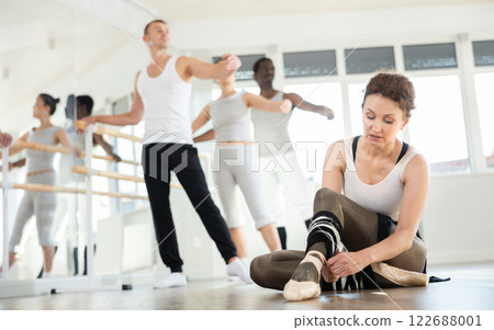 Woman dancer tying ribbons on pointe shoes 122688001