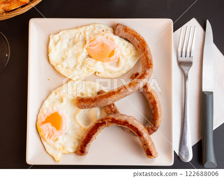 Breakfast with sunny side up eggs and grilled butifarra sausages 122688006