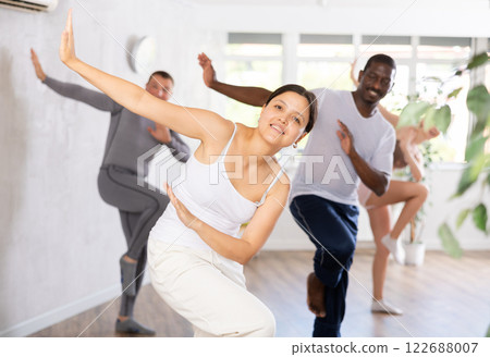 Young woman practicing dancing in group in studio Young woman practicing dancing in group in studio 122688007