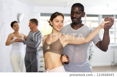 Young woman and African American man dancing ballroom dances in pair Young woman and African American man dancing ballroom dances in pair 122688045