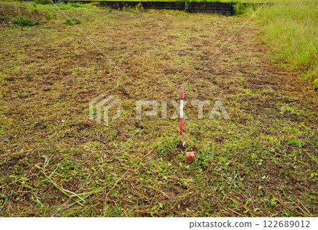 Boundary markers surveyed and installed before land development Boundary markers surveyed and installed by a land and house surveyor and farmland with grass cut 122689012