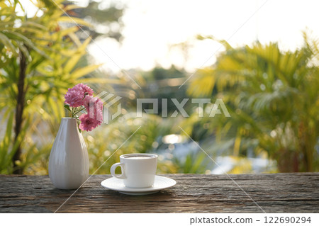 ceramic coffee cup and a white vase of rose flowers cozy garden view 122690294