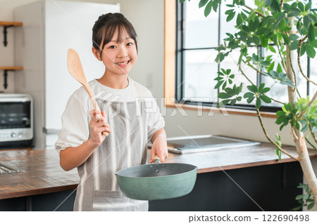 Elementary school and junior high school girls wearing aprons in the kitchen at home Elementary school and junior high school girls wearing aprons in the kitchen at home 122690498