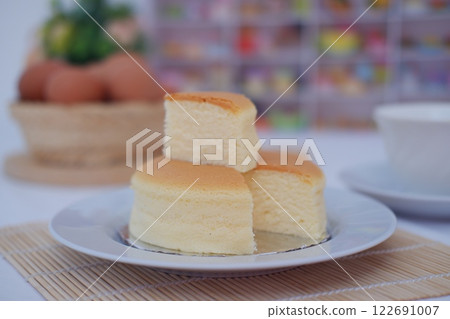 Cheesecake on white plate and eggs on bamboo mat 122691007