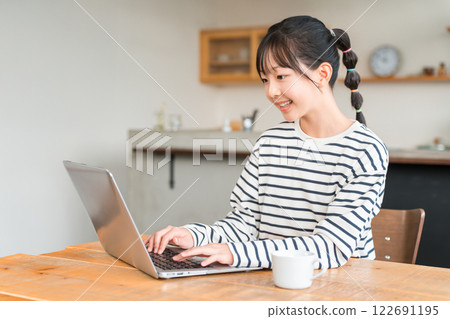 Elementary school and junior high school girls using a computer in the living room/study corner at home Elementary school and junior high school girls using a computer in the living room/study corner at home 122691195